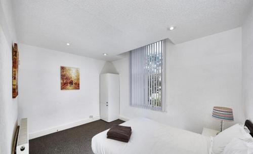 a white bedroom with a bed and a window at No 4 AT MANNERING, LARGE 1 BED NEAR SEFTON PARK in Liverpool