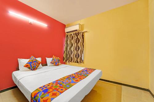 a bedroom with a bed with red and yellow walls at FabExpress Maruthi in Coimbatore