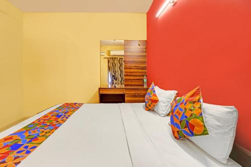 a bedroom with a white bed with a red wall at FabExpress Maruthi in Coimbatore