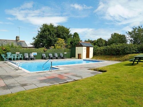 a swimming pool with chairs and a table in a yard at Maple Lodge in Newton Abbot
