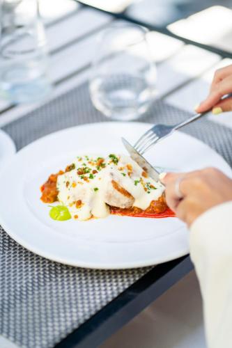 a person eating a plate of food on a table at Abba Playa Gijón in Gijón