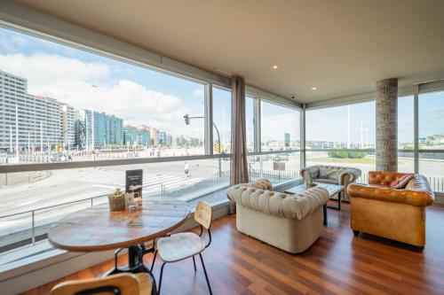 a living room with a large window and a table and chairs at Abba Playa Gijón in Gijón