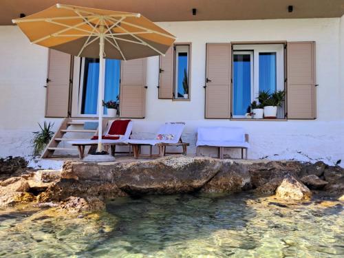 a patio with an umbrella and chairs and water at Artis Blue Relax in Himare