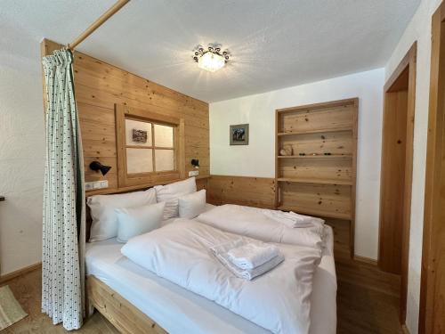 a bedroom with a white bed with a wooden wall at Apartpension Schollberg in Sankt Anton am Arlberg