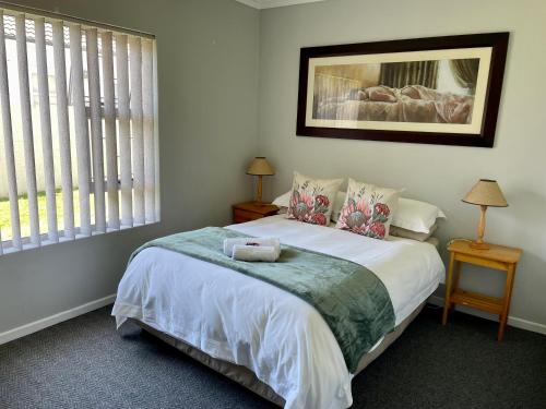 a bedroom with a bed with white sheets and a window at Langebaan Country Club Self Catering 1A in Langebaan