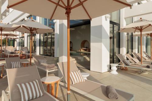 a patio with tables and chairs with umbrellas at Hotel Preko Ugljan Island, Curio Collection By Hilton in Preko