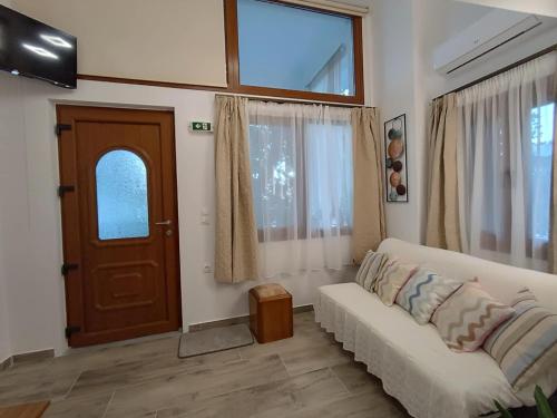 a living room with a white couch and a door at Isidora Apartments in Zagora