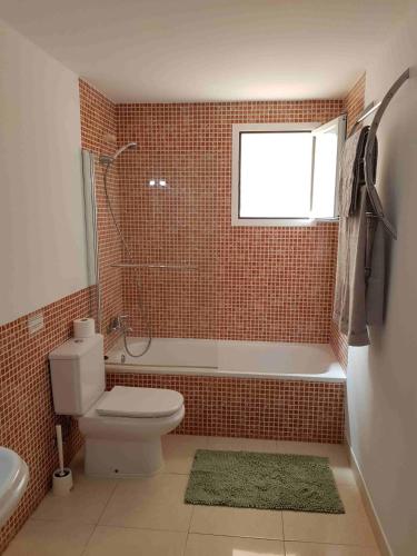 a bathroom with a toilet and a tub and a window at Ferienwohnung Lika in Cala Bona