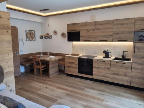 a kitchen with wooden cabinets and a sink and a table at Posta Apartments in Colle Santa Lucia