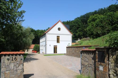 a white house with a stone wall next to a road at Apartment House - Oparno 16 in Velemín