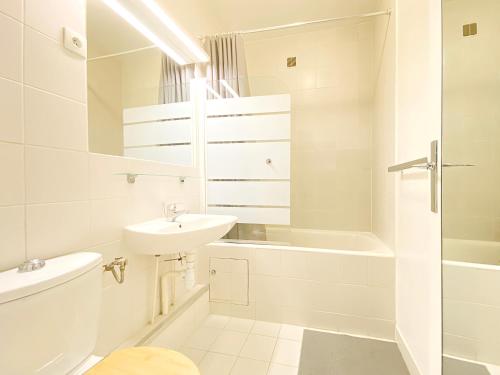 La salle de bains blanche est pourvue d'un lavabo et d'une baignoire. dans l'établissement Cosy flat with the view of Eiffel Tower, à Paris