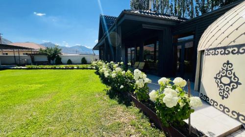 a house with a row of flowers in the yard at Asylai Guesthouse in Naryn