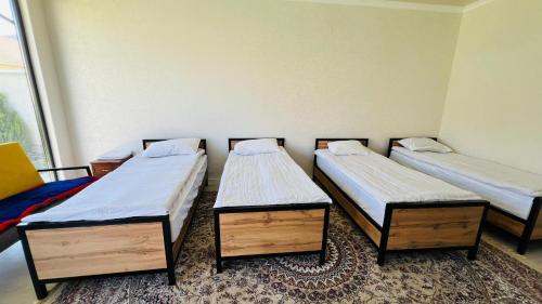 a group of three beds in a room at Asylai Guesthouse in Naryn