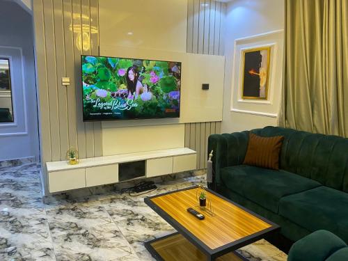 a living room with a green couch and a flat screen tv at Live By The Water 2-Bed-Apt With Starlink SuperFast Speed Wi-Fi And Secured in Amuwo
