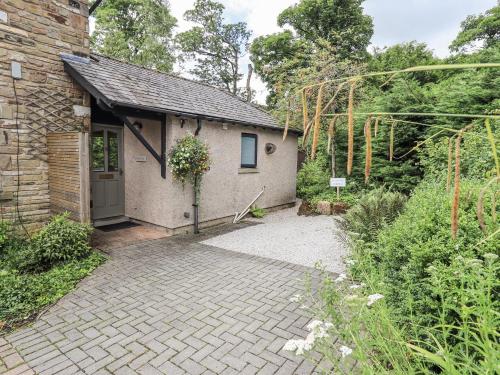 a brick building with a door in a garden at Doe Foot Cottage in Ingleton