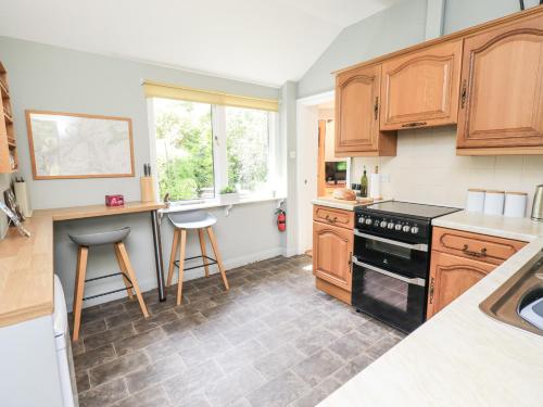 a kitchen with wooden cabinets and a black stove top oven at Doe Foot Cottage in Ingleton