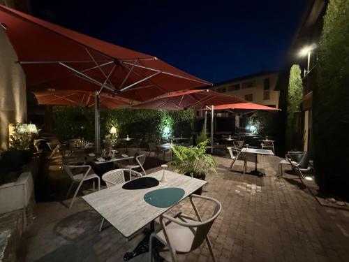 an outdoor patio with tables and umbrellas at night at Le Victor Hugo - Hôtel et Restaurant - Logis Hôtels in Saint-Céré