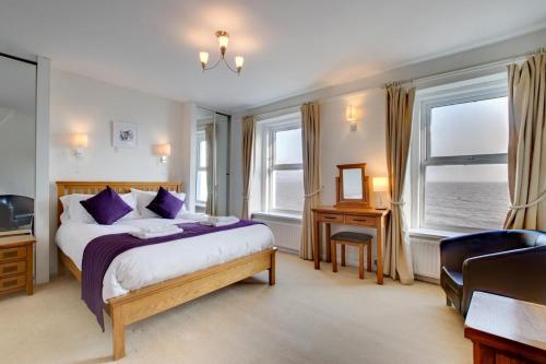 a bedroom with a bed and a desk and windows at St Judes in The Mumbles