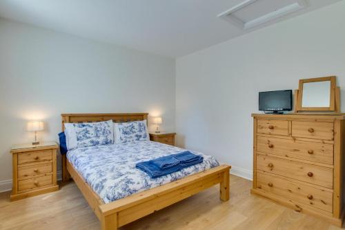 a bedroom with a bed and two dressers and a tv at Bluebell Cottage in Penclawdd