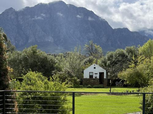 a house in a field with a mountain in the background at Welbedacht Game & Nature Reserve in Tulbagh