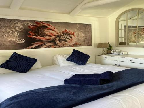 a white bed with blue pillows on top of it at Welbedacht Game & Nature Reserve in Tulbagh