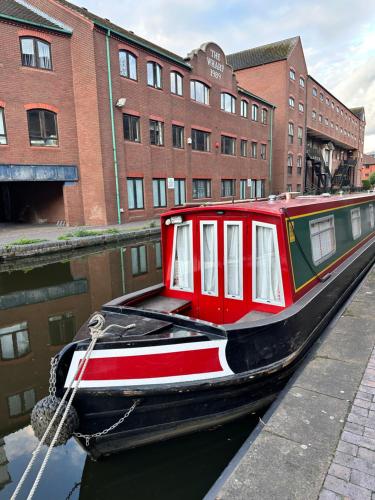 a red boat is docked next to a building at Enjoy city living in this one-bedroom flat, complete with a balcony and secure parking in Birmingham city center in Birmingham