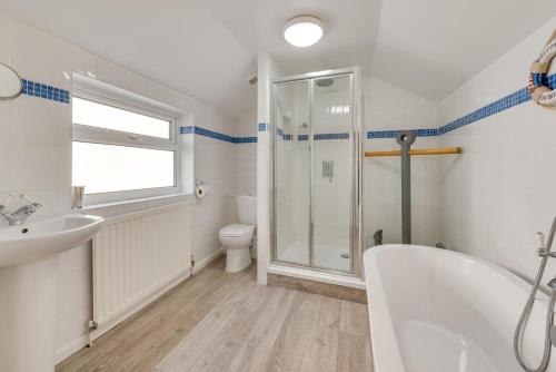 a bathroom with a tub and a toilet and a sink at Arfryn in The Mumbles