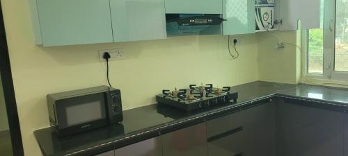 a kitchen with a microwave and a tv on a counter at OZY Homestay in Rāiwāla