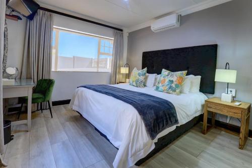 a bedroom with a large bed with a desk and a window at African Oceans Manor on the Beach in Mossel Bay
