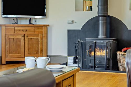 a living room with a fireplace with a stove at Northwood Farm - The Granary in Ellastone