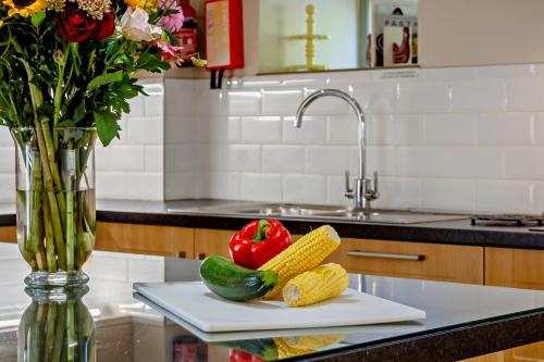 a counter with a vase with vegetables on a cutting board at Northwood Farm - The Granary in Ellastone