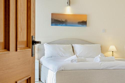 a bedroom with a bed with white sheets and pillows at Northwood Farm - The Granary in Ellastone