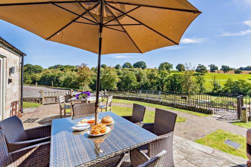 a table with an umbrella on a patio at Northwood Farm - The Granary in Ellastone