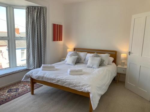a bedroom with a bed with white sheets and a window at Beechwood House in The Mumbles
