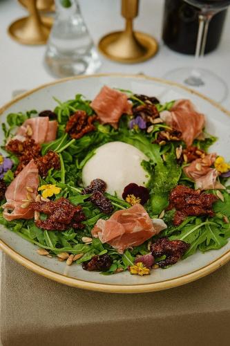 a plate of salad with meat and vegetables on a table at Grand Royal Hotel in Poznań