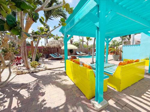 a patio with yellow and blue furniture next to a pool at Aruba Palms Escape Suites in Palm-Eagle Beach