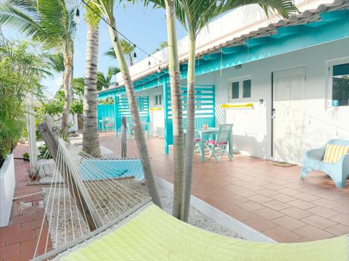 a hammock in front of a house with palm trees at Aruba Palms Escape Suites in Palm-Eagle Beach