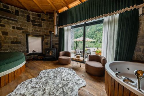 a bedroom with a bath tub and a bed and a room with a fireplace at Oria Hotel Boutique in Çamlıhemşin