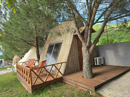 a small tree house with a deck and a tree at Ioannina Camping- Glamping in Neo Mpizani