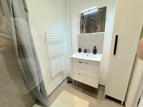 une salle de bain blanche avec un lavabo et un miroir dans l'établissement ⁂ 2P Rénové à 100m de la plage, à Nice