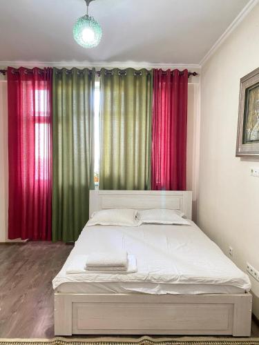 a bedroom with a bed with red and green curtains at Логвиненко 32 in Akchiy