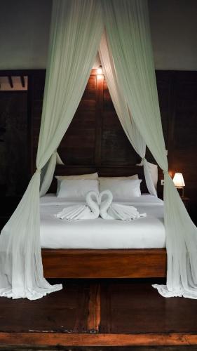 a bed with white sheets and drapes on it at The Karu Cabin in Penebel