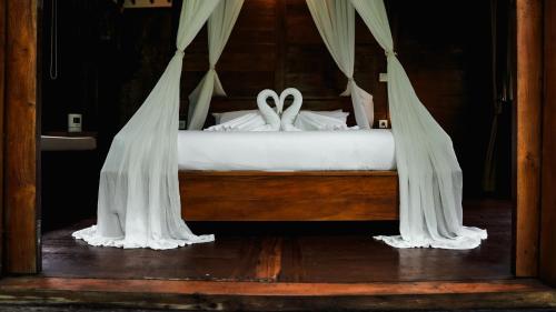 a bed with white drapes and two white wedding rings at The Karu Cabin in Penebel