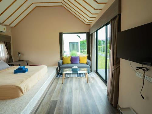 a bedroom with a bed and a couch and a tv at Berghaus101khaoyai in Nakhon Ratchasima