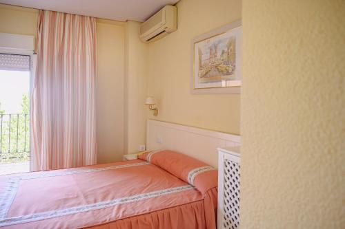 a small bedroom with a bed and a window at Hotel Paraíso in Lanjarón
