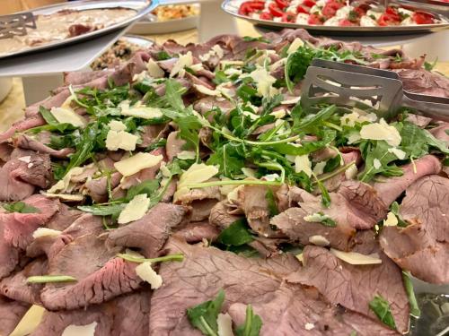 a large pizza with meat and greens on a table at Park Hotel Villa Americana in Rodi Garganico