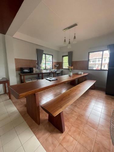 a large dining room with a wooden bench in a room at Baan Plumeria บ้านภูมิเรีย in Phetchaburi