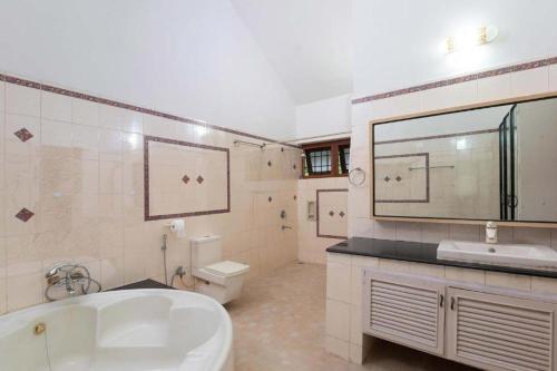 a bathroom with a tub and a sink and a toilet at Dwaraka inn -Premium Pool villa and event venue in Coimbatore