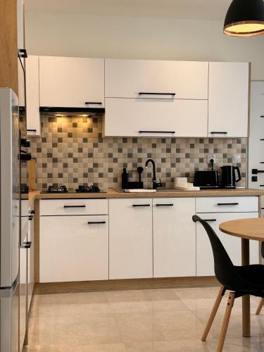 a kitchen with white cabinets and a table and a chair at Rezidence MAHENOVA 2 in Golčŭv Jeníkov