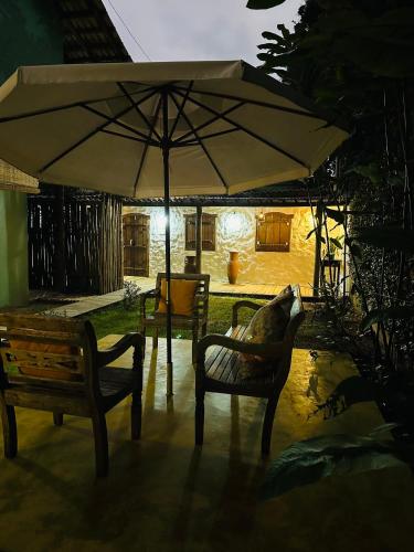 a patio with two chairs and an umbrella at Pousada Amor de Casa in Trancoso